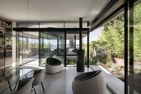 In the office, a custom floor-to-ceiling bookcase complements understated office furniture, while plush Ottoman Armchairs by Ligne Roset and a Rais gas fireplace assemble to create a simple lounge space, with views all the way to the ocean.