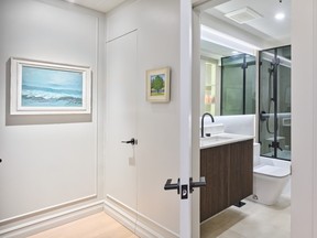 In the condo's bathrooms, modern smoked glass and LED strip lighting complement back-lit mirrors and ribbed cabinet panels chosen for dramatic effect.