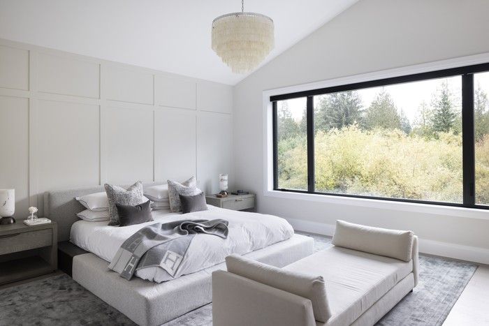  The primary bedroom features a clean layout and soft grey palette, with a wainscotted accent wall for texture.