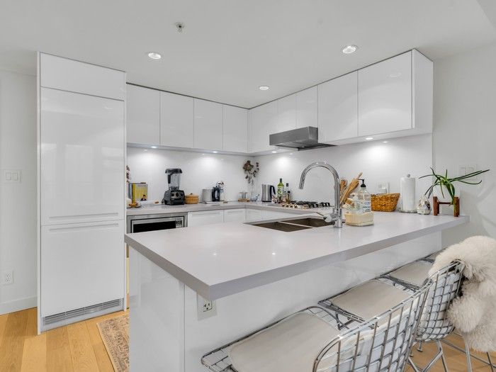  This upper-floor condo has a brightly lit kitchen with contemporary white cabinets and wood floors.