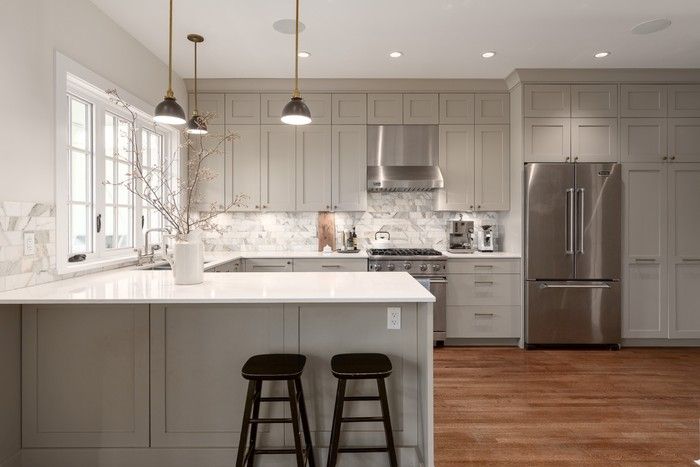  Elegant kitchen finished with bespoke cabinets, engineered stone counters and marble backsplash.
