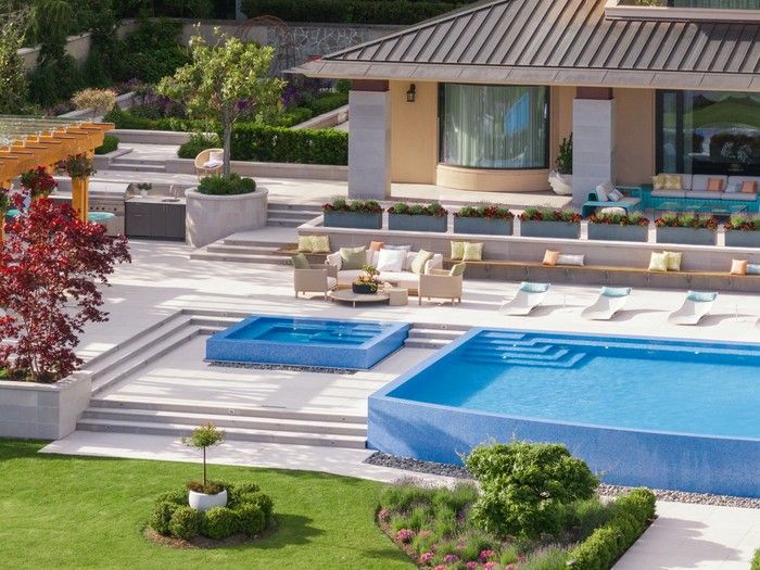  Tiered concrete-tile patios follow the natural slope of the landscape, separated by large planters to break up the expanse and create seating, dining and relaxing zones.