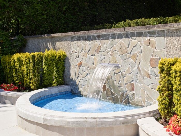  On the west side of the home, a cutting garden, surrounded by hedges and a wrought-iron arch, blooms seasonally with range of flowers, opposite a trough-style water fountain.