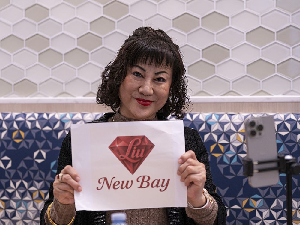 Weihong Liu holds up a sign during her interview with Postmedia at the Tsawassen Mills Shopping Mall in Delta, BC, May, 18, 2025. Liu has bid to acquire Hudson's Bay stores in Canada. Weihong Liu holds up a sign during her interview with Postmedia at the Tsawassen Mills Shopping Mall in Delta, BC, May, 18, 2025. Liu has bid to acquire Hudson's Bay stores in Canada.