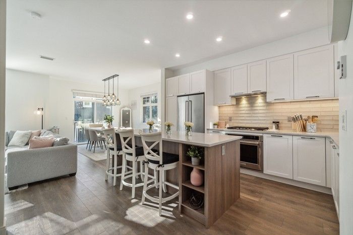  Kitchen has white Shaker-style cabinets, quartz counters, stainless-steel KitchenAid appliances, and a generous-sized island with plenty of built-in storage.
