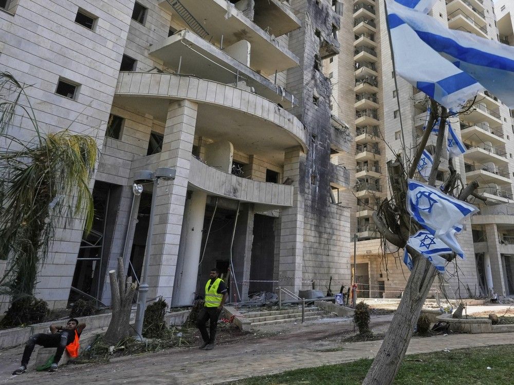   Un agent de sécurité israélien se tient à l'entrée d'un bâtiment résidentiel frappé par un missile lancé depuis l'Iran, à Petah Tikva, Israël, le lundi 16 juin 2025.