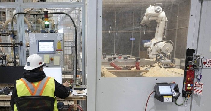 A worker uses a computer to monitor robotic workers at the Intelligent City manufacturing plant. A worker uses a computer to monitor robotic workers at the Intelligent City manufacturing plant.