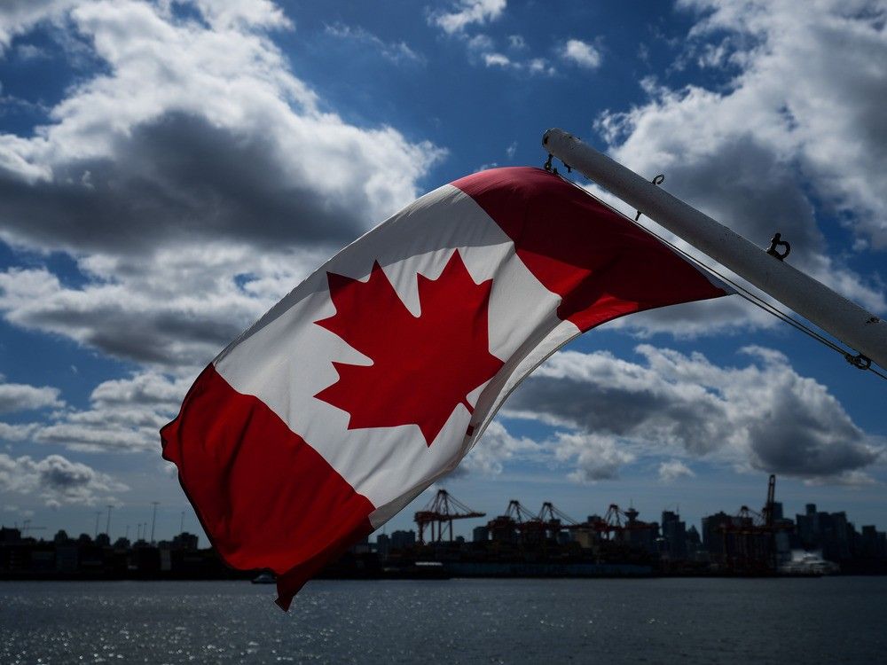 A Canadian flag flies on a boat with the downtown Vancouver skyline in the background. A Canadian flag flies on a boat with the downtown Vancouver skyline in the background.