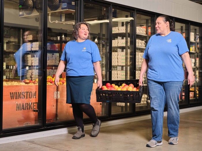 Staff bring in apples to the large fridges at the food bank's new location.