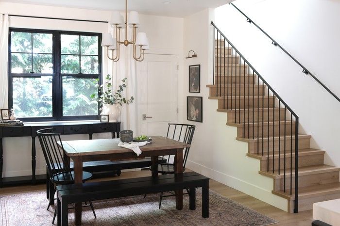  A mix of seating, including kid-friendly benches and spindle-back Kennamer chairs from Wayfair, surround the dining table, complementing a vintage console and Keenan Chandelier by Crystorama.