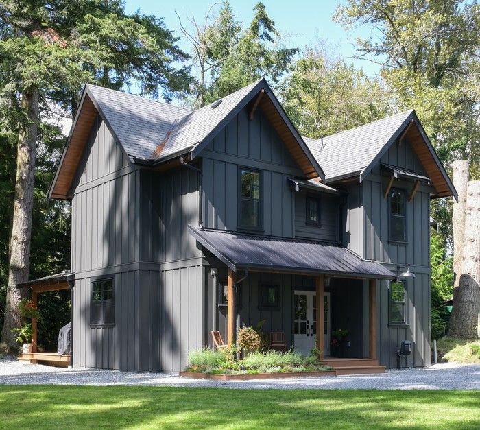  A modern take on a European cottage: tucked into a forested corner of a Langley lot, this home pairs vertical board-and-batten siding with warm wood accents and a steep gabled roofline, creating a cozy, cottage-inspired feel with modern edge.