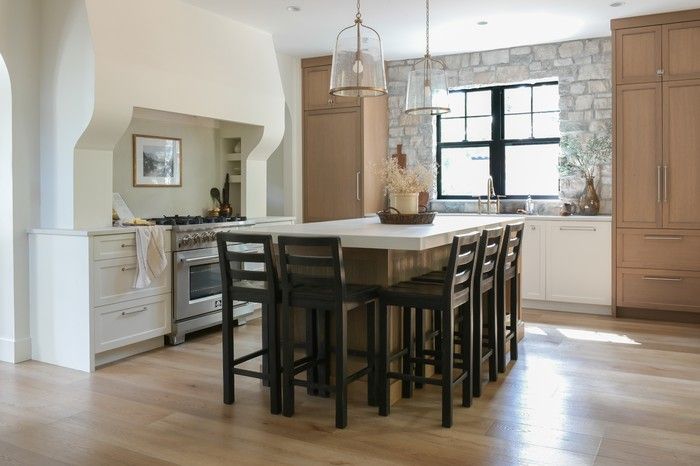  Crisp white and rift-cut oak cabinetry with polished-chrome hardware leans clean and modern, while a Caesarstone-topped kitchen island adds reeded side panelling for visual interest, under Madison pendant lights from Capital Lighting Fixture Company.