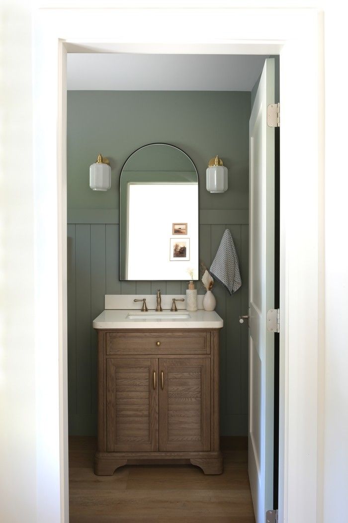  Designer Ashley Spencer chose a bold green hue – Sherwin Williams Evergreen Fog – to colour-drench the powder room, painting walls and wainscotting in the same shade for a dramatic effect.