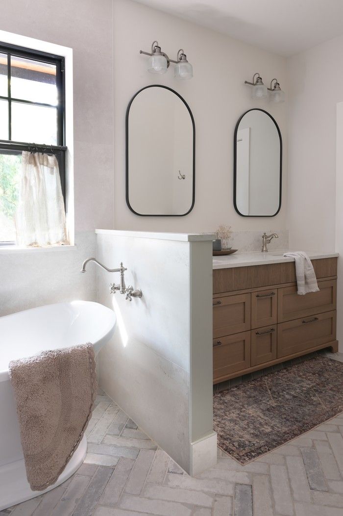  The primary bath delivers spa vibes with large-format tile, quartz ledges and a classic freestanding tub under the window.