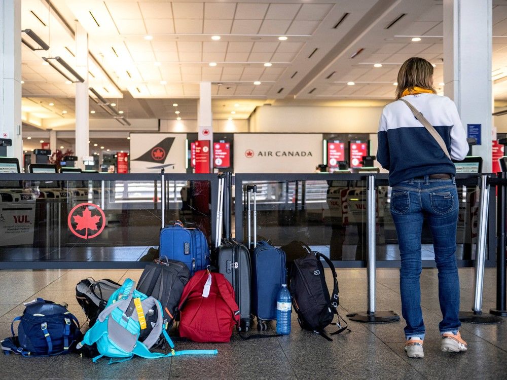 A passenger waits for information as Air Canada flights are slated to resume as early as this evening at Pierre-Elliott Trudeau Airport in Montreal, Quebec, on August 19, 2025. Air Canada flight attendants ended their strike after reaching a tentative deal with the carrier, which said it will work to restore full service for its 130,000 daily passengers. Roughly 10,000 flight attendants walked off the job after midnight Saturday, insisting Air Canada had failed to address their demands for higher pay and compensation for unpaid ground work, including during boarding. (Photo by ANDREJ IVANOV / AFP)