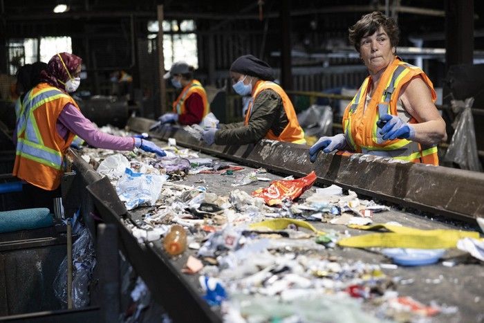 Workers at a conveyor belt at a recycling depot.