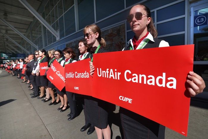 Flight attendants stood silently for more than 30 minutes curbside outside the departures level at Vancouver International Airport on Monday. Flight attendants stood silently for more than 30 minutes curbside outside the departures level at Vancouver International Airport on Monday.