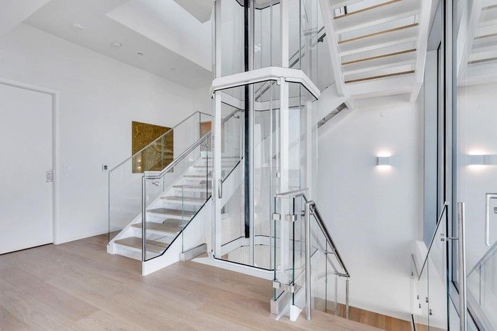  The steel and glass staircase, next to the glass-encased elevator, connects the three floors and features bleached white oak stairs.