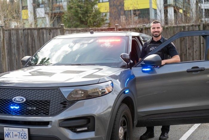 Const. Sam Zacharias, Port Moody Police media relations officer poses beside one of the police department’s hybrid Ford Interceptor vehicles in the rear parking lot of the Port Moody Police department. Const. Sam Zacharias, Port Moody Police media relations officer poses beside one of the police department’s hybrid Ford Interceptor vehicles in the rear parking lot of the Port Moody Police department.