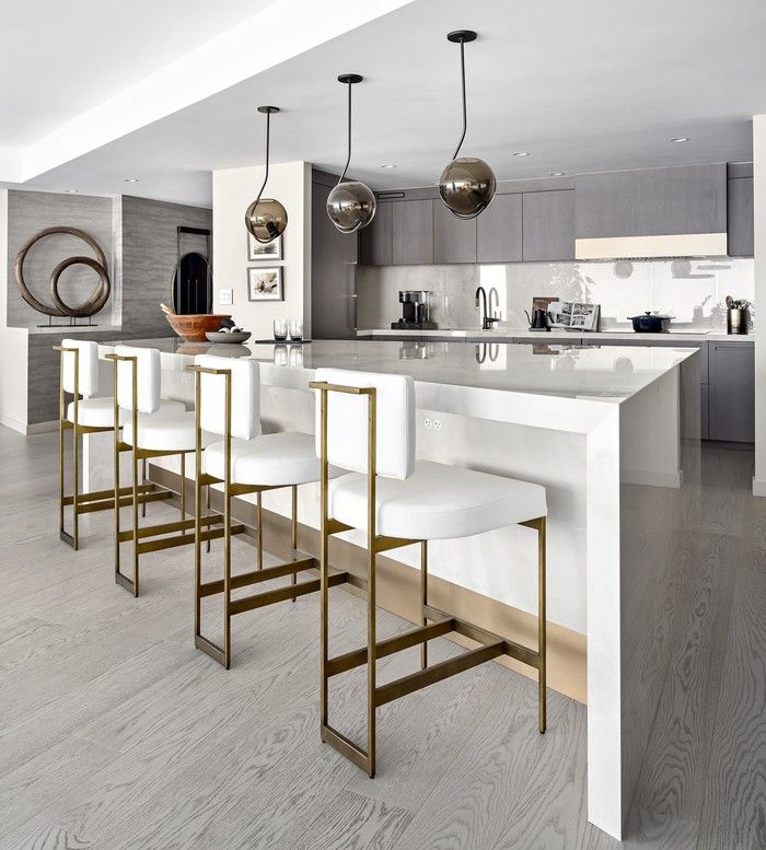  A wedge-shaped island commands presence in mitred Dekton, with a brushed bronze kickplate. Roll & Hill pendants emphasize the unique layout, while cabinetry refaced by Luminous Cabinets in a cool-toned veneer keeps the lines sleek, with a custom hood fan subtly blending in.