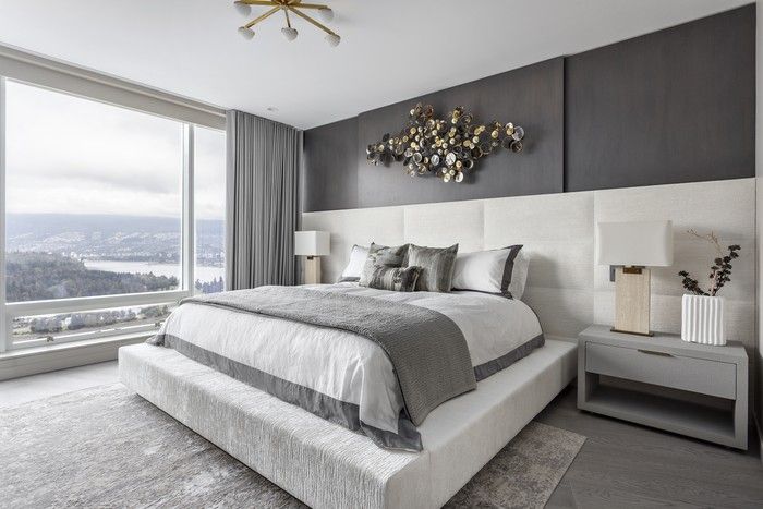  The principal bedroom takes design cues from a luxury hotel, centring on a custom-designed bed with an expansive upholstered headboard and plinth, paired with Restoration Hardware linens and Interlude Home nightstands, from Once a Tree Furniture. A stepped wood wall treatment overhead frames a Jonathan Adler wall sculpture.
