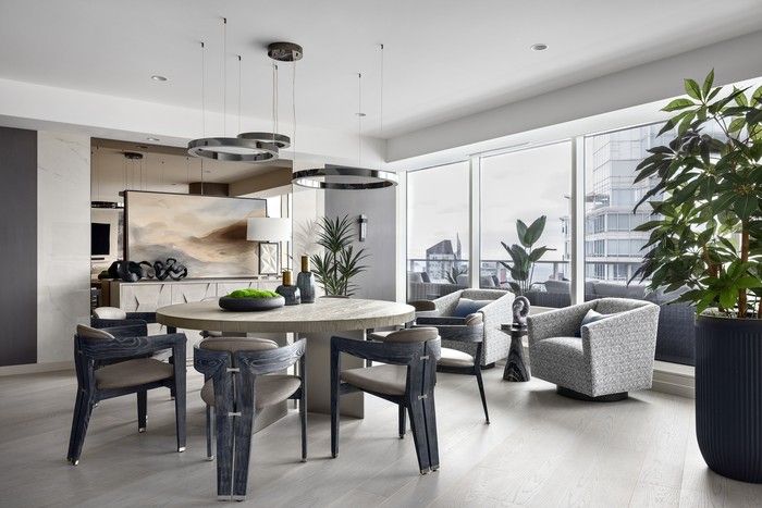  In the dining room, Lui paired a six-foot-wide Restoration Hardware table, featuring a wire-brushed wood top and brushed metal base, with Interlude Home chairs from Once a Tree Furniture. A smoked mirror wall doubles the impact of a commissioned artwork by Vancouver painter Wendy Jia, while a ring-shaped chandelier from Avenue Lighting adds extra drama.