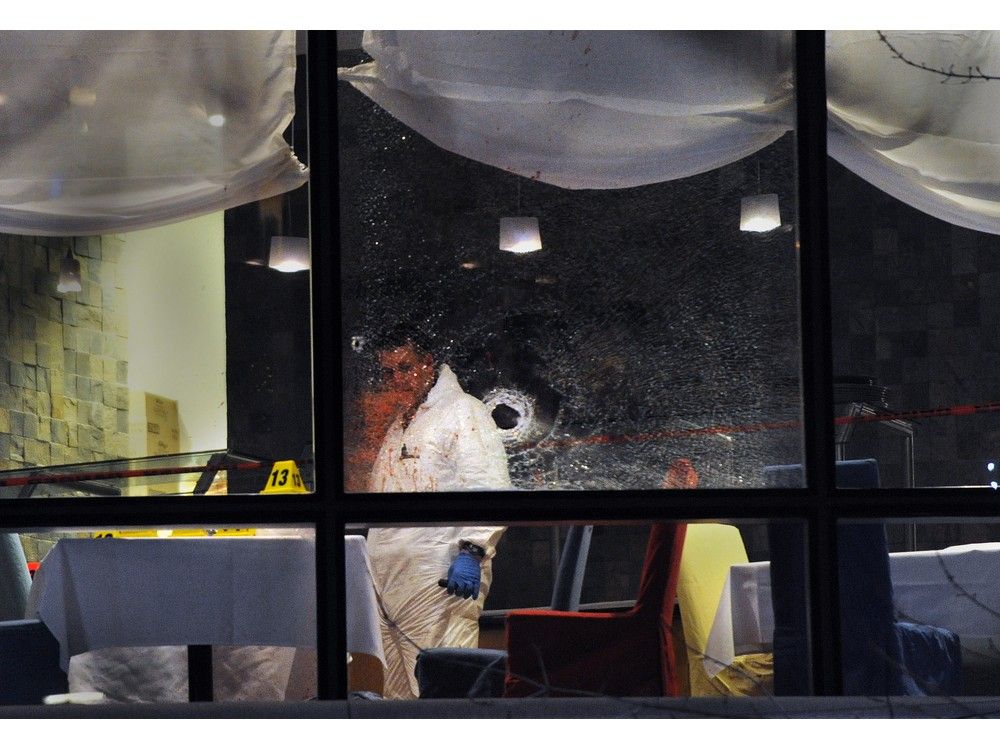   Les enquêteurs de la police regardent un trou de balle apparent au restaurant Sheraton Vancouver Wall Center où Sandip Duhre a été abattu en janvier 2012