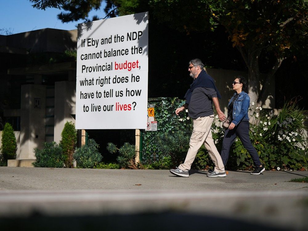 Pedestrians walk past another provincial election-related sign outside the home of billionaire Lululemon founder Chip Wilson in Vancouver on Oct. 10, 2024. Pedestrians walk past another provincial election-related sign outside the home of billionaire Lululemon founder Chip Wilson in Vancouver on Oct. 10, 2024.