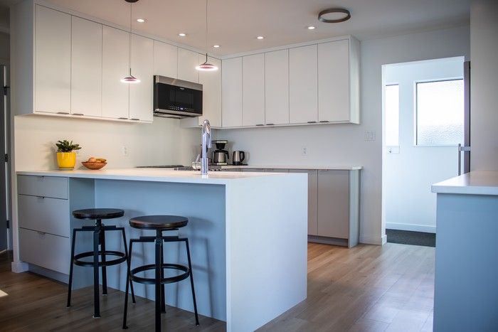 Pale oak floors and white-and-grey cabinetry brighten the open kitchen-dining-living area.  Pale oak floors and white-and-grey cabinetry brighten the open kitchen-dining-living area.
