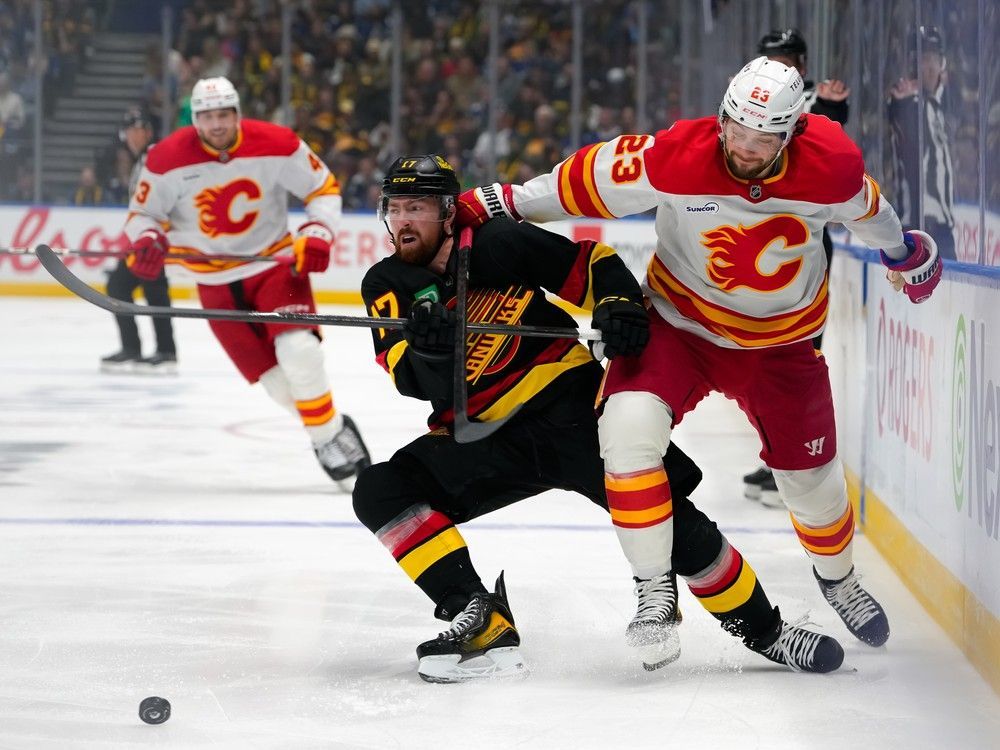Filip Hronek of the Vancouver Canucks and Justin Kirkland of the Calgary Flames battle for the puck during the second period of their NHL game at Rogers Arena on October 9.