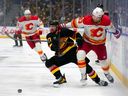 Filip Hronek of the Vancouver Canucks and Justin Kirkland of the Calgary Flames battle for the puck during the second period of their NHL game at Rogers Arena on October 9.