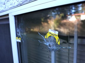 A bullet hole into he window and blind of a home where an extortion-related shooting injured a woman in Surrey on the weekend.