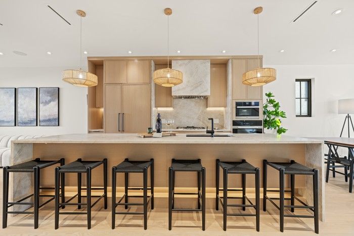  A natural stone-topped island anchors the kitchen with seating for six, and while slim-shaker oak cabinetry create a warm, tailored kitchen.