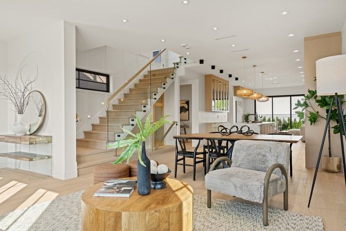 An open main floor keeps family life connected, with the glass-railed stair, dining area, and front sitting room all flowing toward the kitchen at the centre of the home.