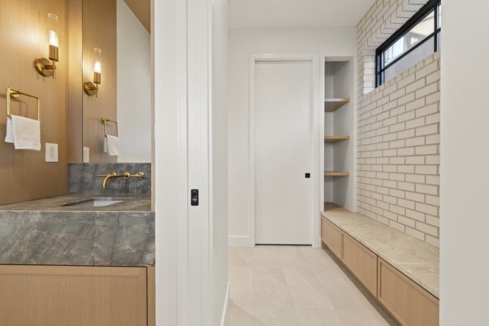  Off the laneway-side entry, a hardworking mud room borrows brick from the exterior, adding a built-in bench, storage, tiled floors and a connected powder room, so everyday mess stays here, not at the front door.