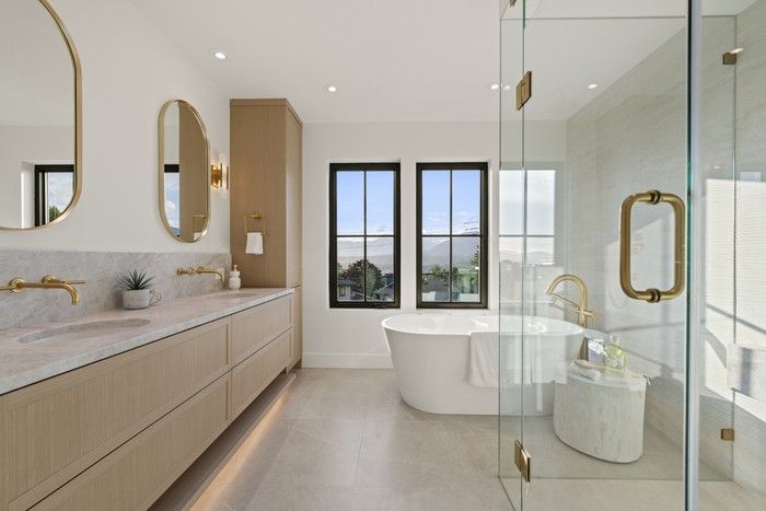  The primary ensuite pairs a freestanding tub with a generous glass-enclosed shower – now a rarity in many new builds –finished with natural stone, oak millwork and brushed brass fixtures.