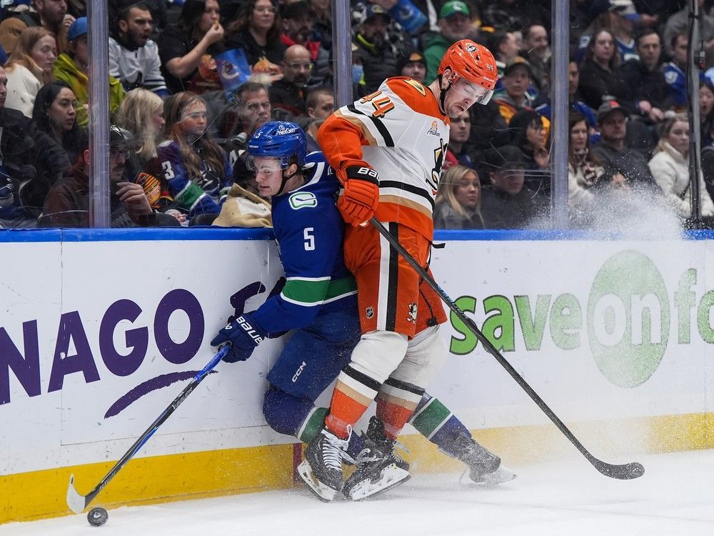 Anaheim Ducks' Ross Johnston (44) checks Vancouver Canucks' Tom Willander (5) during an NHL hockey game, in Vancouver, on Thursday.