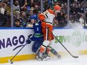Anaheim Ducks' Ross Johnston (44) checks Vancouver Canucks' Tom Willander (5) during an NHL hockey game, in Vancouver, on Thursday.