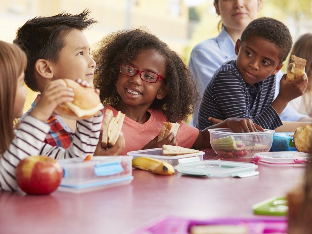  young school kids eating lunch talking at a table together