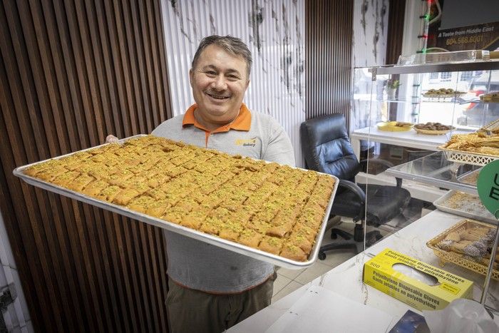 A smiling man holding a tray of pastries
