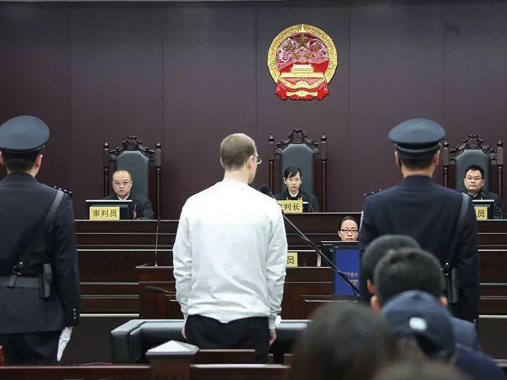 Robert Schellenberg stands in front of Chinese judges