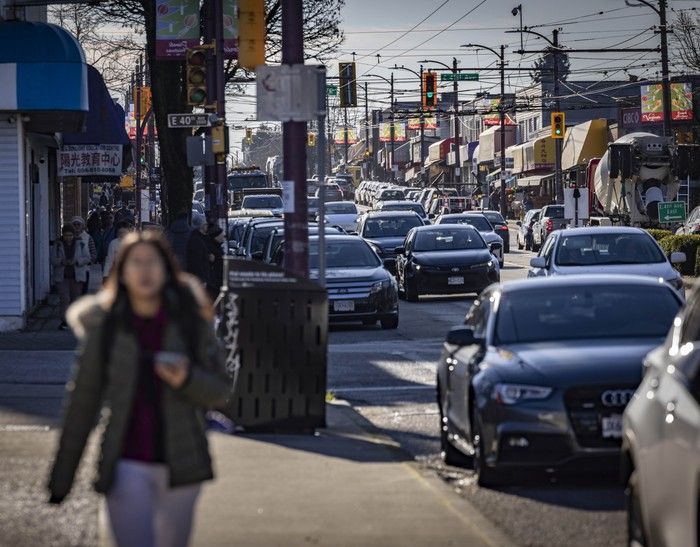 A woman walks down a busy stretch of Victoria Drive in Vancouver.