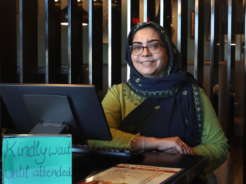 A smiling woman stands behind the counter at a restaurant