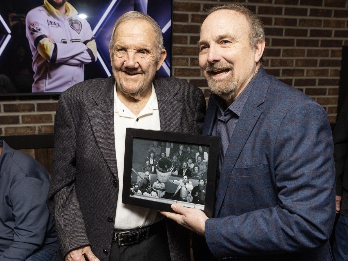 Former New Westminster Bruins coach Ernie (Punch) McLean, left, with a photograph of him throwing a garbage can, and the photographer who took it, Craig Hodge, at Woody's Pub in Coquitlam on March 5.
