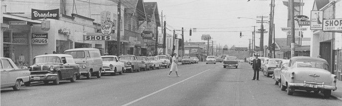 Ca. 1964. Langley City looking west on Fraser Highway. Cars can be seen lining the street in both directions. There is a woman in a light colored dress crossing the street on the left and a man in a dark suit standing on the street on the right. Some of the stores that can be seen on the left are Brandow Drugs, Kathy's, Copp Shoes, Langley Rexall Drugs, and the Langley Hotel.  0305 eat streets langley. Langley Advance Newspaper Collection / Salishan Place by the River photo