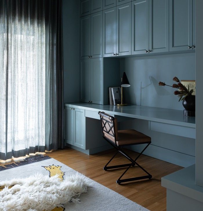 The home office is colour-drenched in Farrow & Ball's Oval Room Blue No. 85, with built-in millwork, sheer drapery and a contemporary take on a bearskin rug by Christopher Farr.