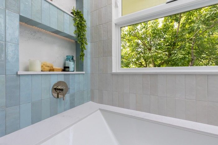 Aqua-hued tiles were positioned on opposite sides of the tub while warm white tiles on the back wall and the tub’s apron complemented the floor tile reminiscent of a tranquil, sandy beach. Aqua-hued tiles were positioned on opposite sides of the tub while warm white tiles on the back wall and the tub’s apron complemented the floor tile reminiscent of a tranquil, sandy beach.