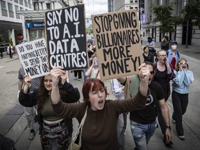 People hold posters reading 'stop giving billionaires more money,' 'say no to AI data centres' and 'protect our Earth, reject AI.'