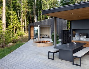 A wraparound deck links the three cabins with spaces for cooking, dining and gathering. At one end, an outdoor kitchen with a barbecue and pizza oven extends living space outdoors, while a pulley-operated enclosure protects the area from weather.