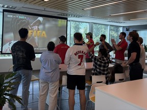 Employees at tech company Clio gather around a screen at their copmany's Burnaby office to watch the World Cup during their workday.